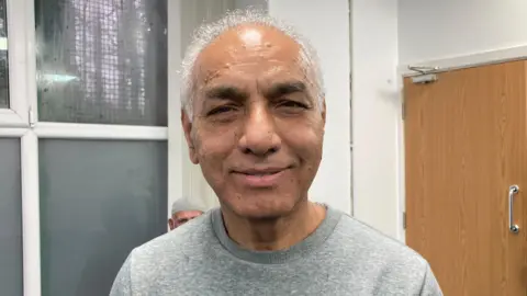 Cathy Minton/BBC Abid Khan, an attendee at pilates sessions at a mosque, has short grey hair and is wearing a grey sweatshirt.