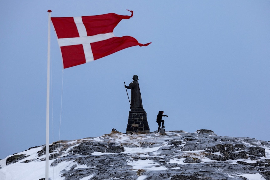 A Danish flag on top of a snow-covered hill in Greenland.