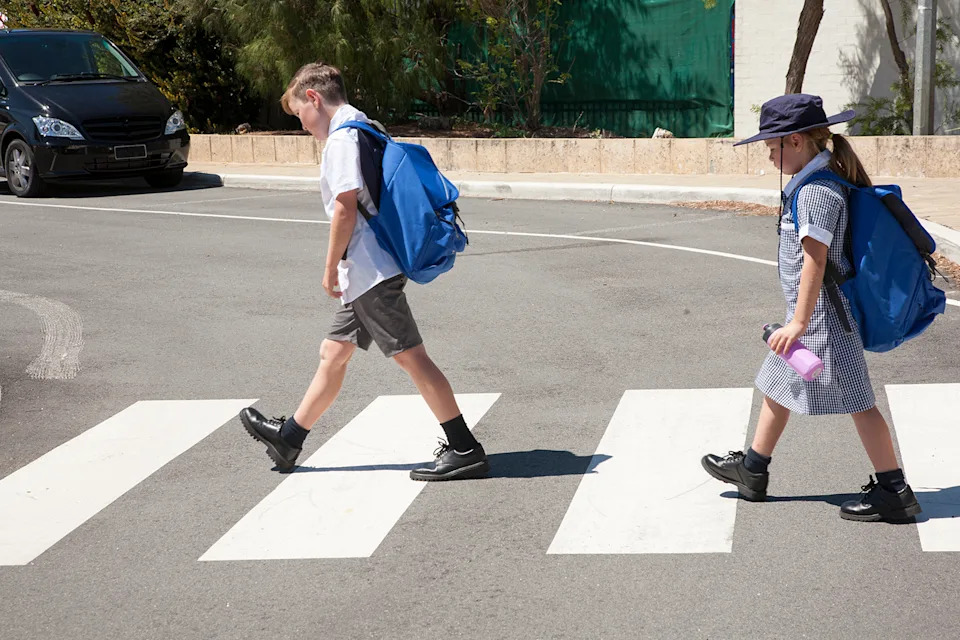 School children crossing the road safely at the cross walk