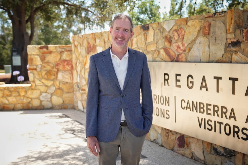A man wears a suit and smiles camly.