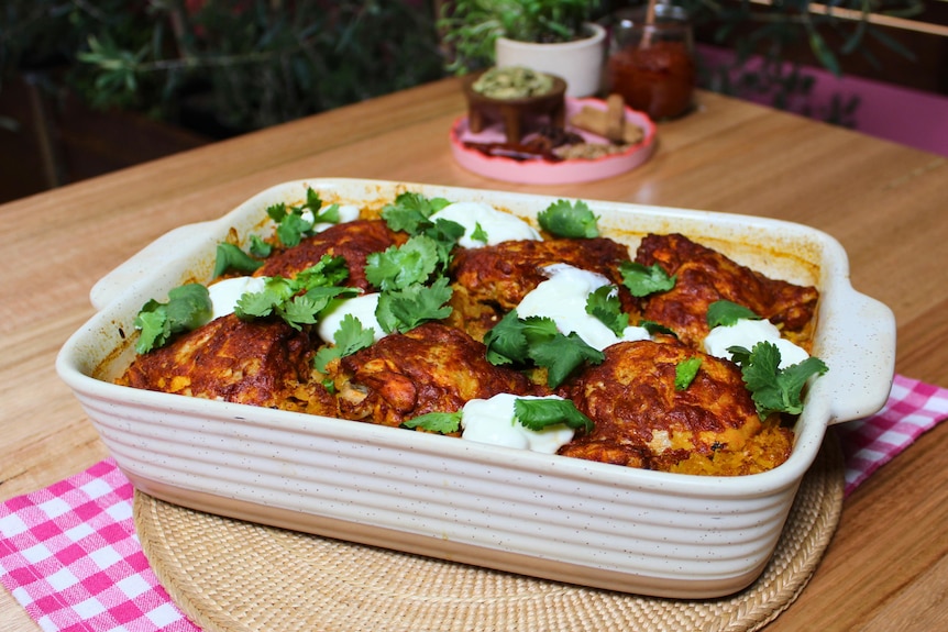 A golden-baked tandoori chicken tray bake with turmeric rice, topped with dollops of creamy yoghurt and fresh coriander,.
