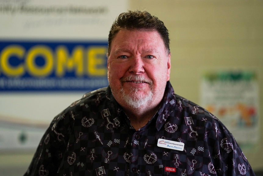 A man with a grey beard and dark hair and a pattern shirt