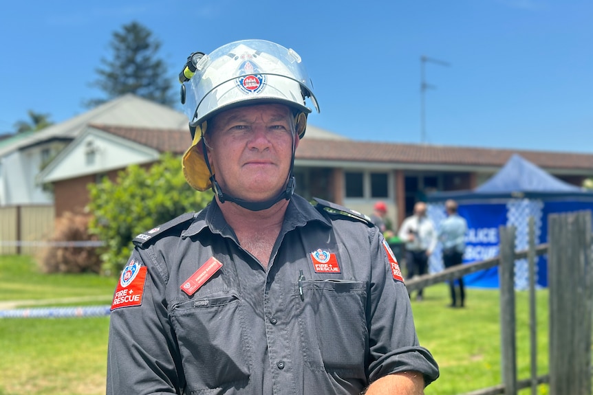 image of firefighter in helmet with neutral facial expression in front of crime scene