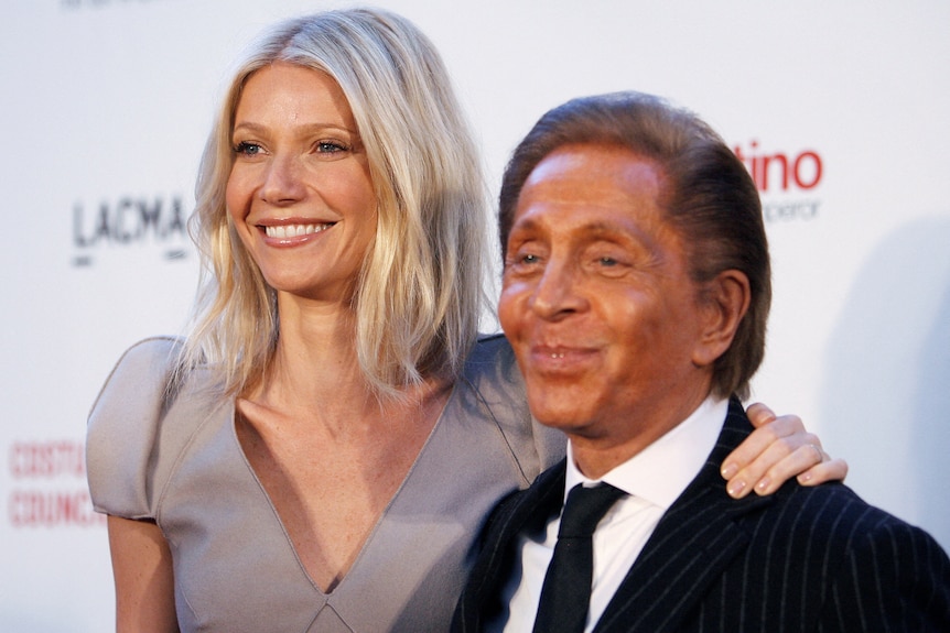 Actress Gwyneth Paltrow and Italian fashion designer Valentino Garavani side by side smiling on a red carpet.