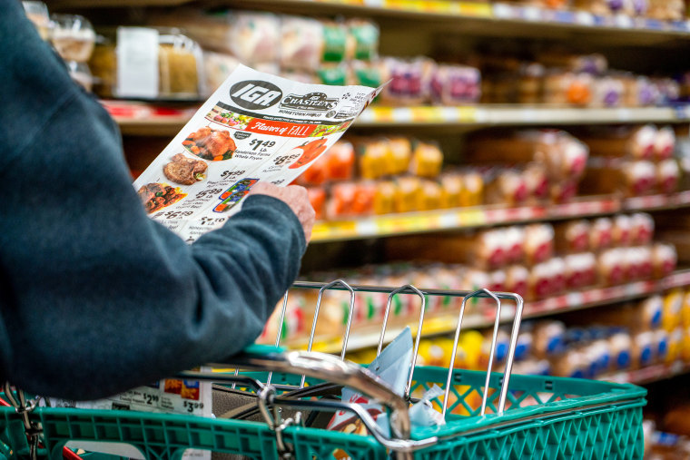 A shopper looks at a sales advertisement at a grocery store.