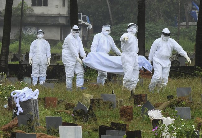 People in protective suits prepare to cremate the body of a 12-year-old boy died of the Nipah virus in India in 2021.