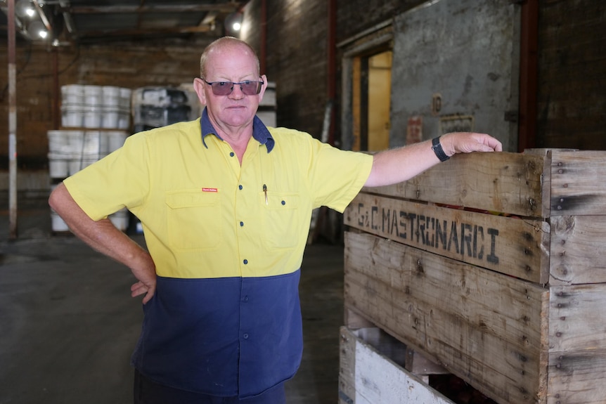 Man standing in high-vis, holding onto a wooden box 