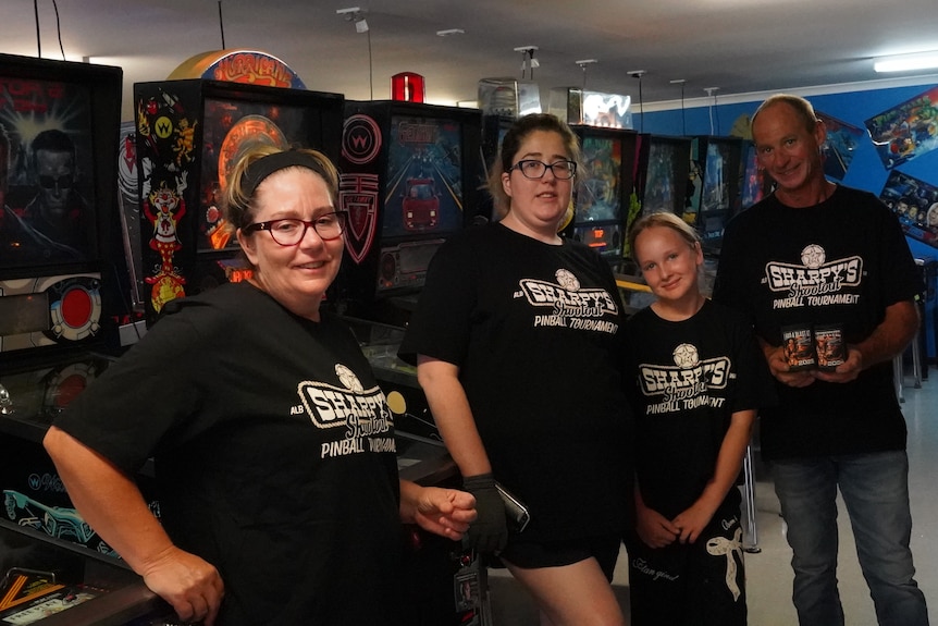 Mr Sharp and his family stand before a row of pinball machines.