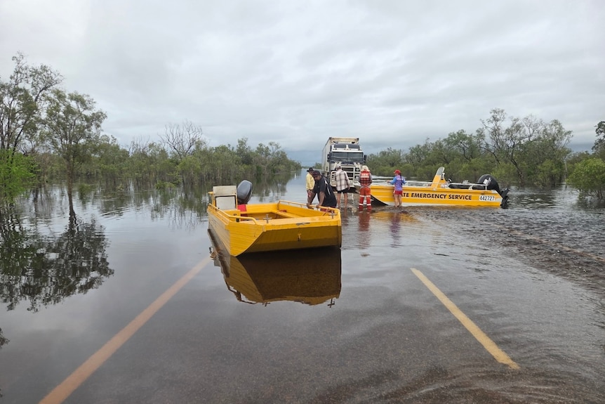 two ses boats on a floaded road next to truck