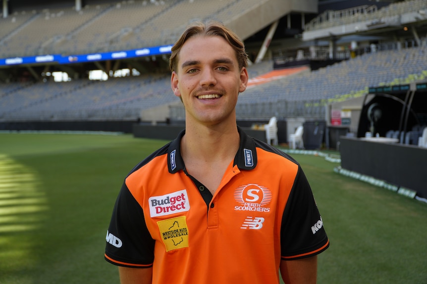Mahli poses for a photo in his orange Scorchers uniform on the cricket ground