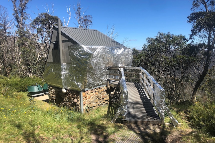 A small outhouse building with a walkway has been wrapped in silver foil material