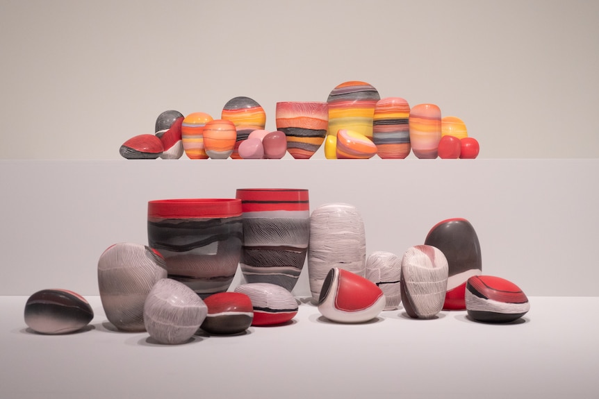 Clusters of colourful porcelain pieces on display in art gallery space