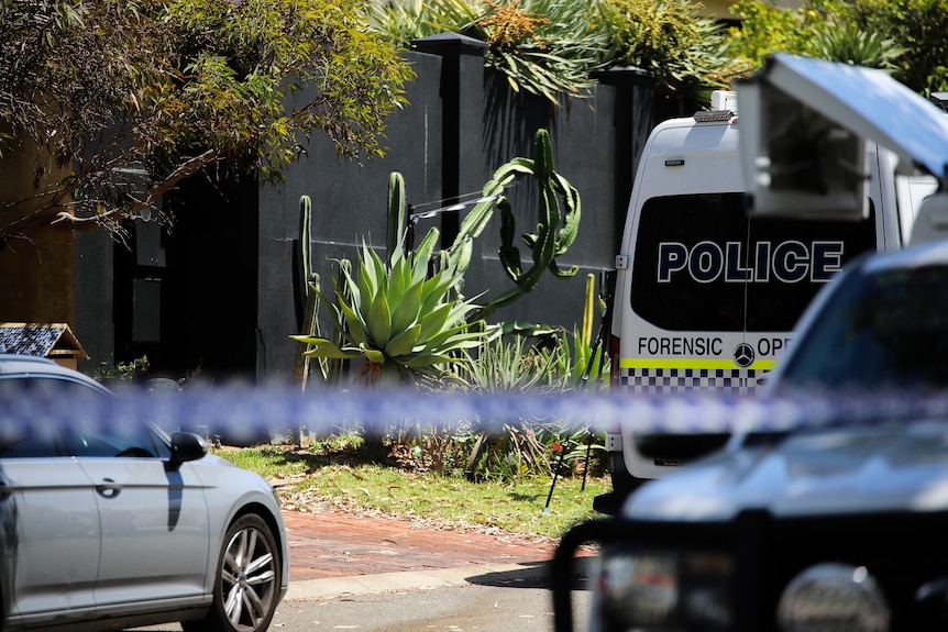 A forensic van parked outside a house with a black wall