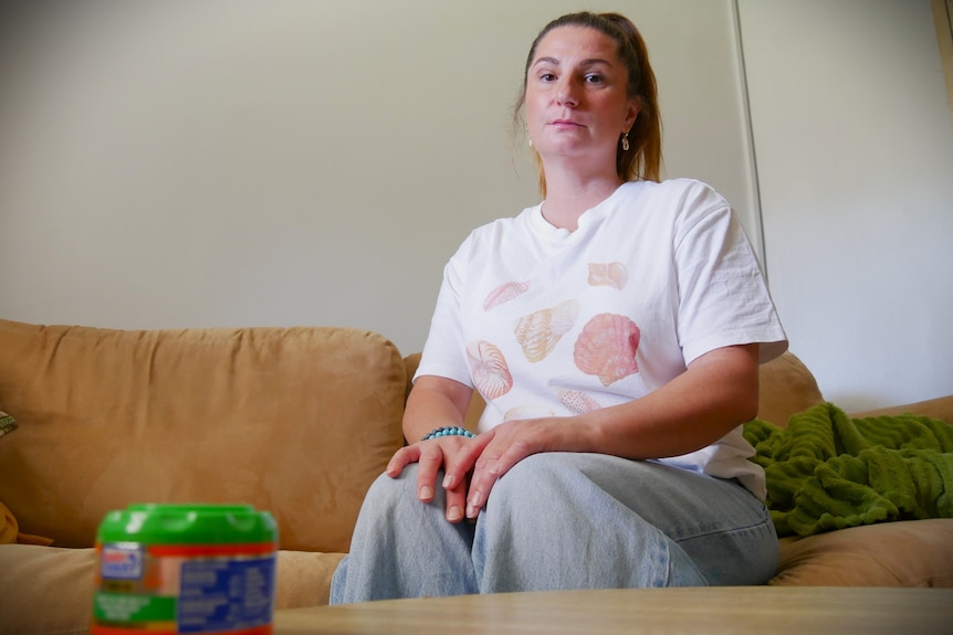 a woman sits on a couch looking serious.