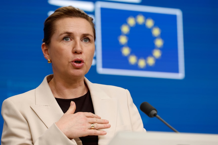 Mette Frederiksen gestures during a press conference in front of a European Union banner