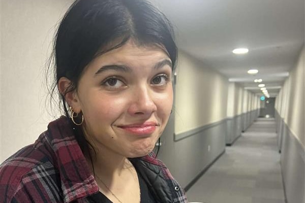 A young woman pulls a funny expression at the camera while holding a soft drink can.