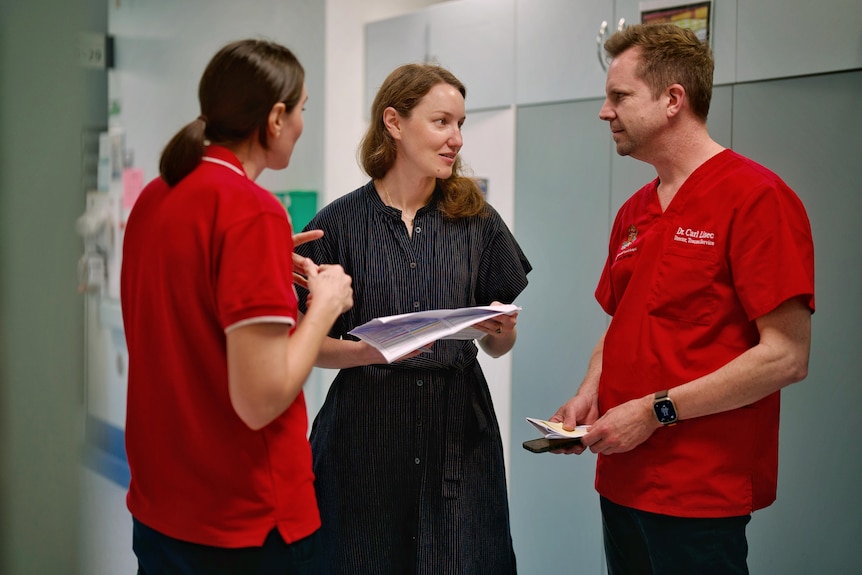 A picture of three medical professionals having a conversation in a corridor