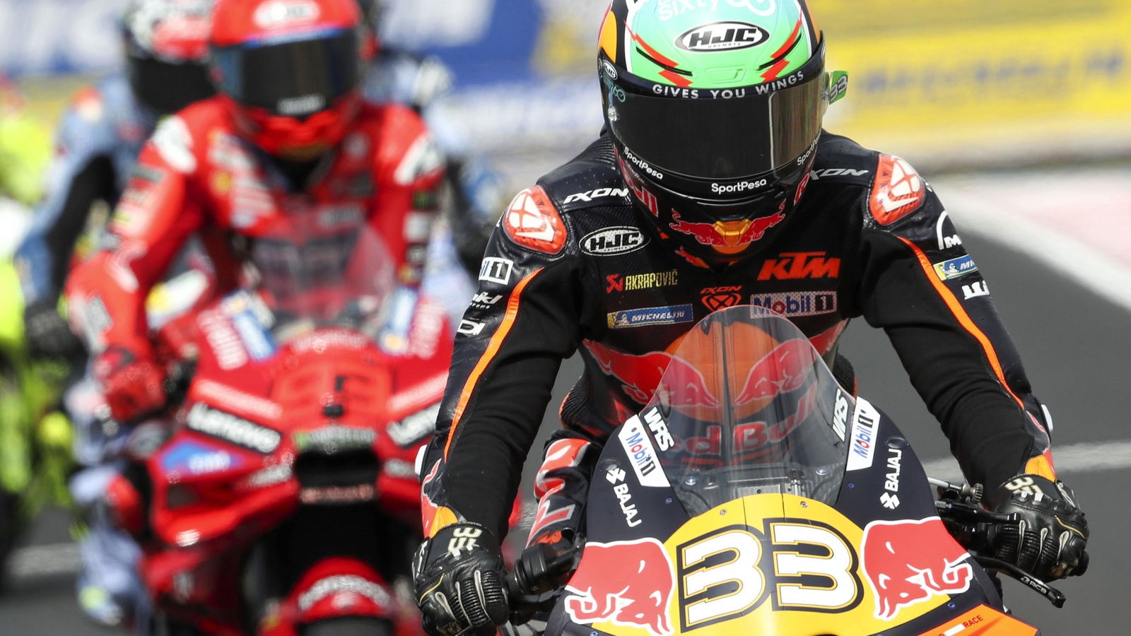 Brad Binder leads Marc Marquez out of the pits during MotoGP 2025.