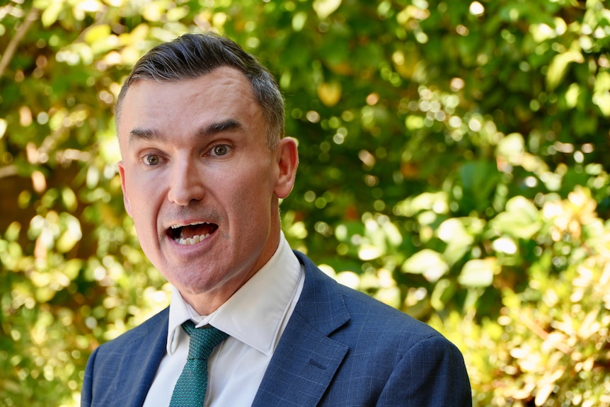 A close up of John Carey mid speech as he delivers a press conference