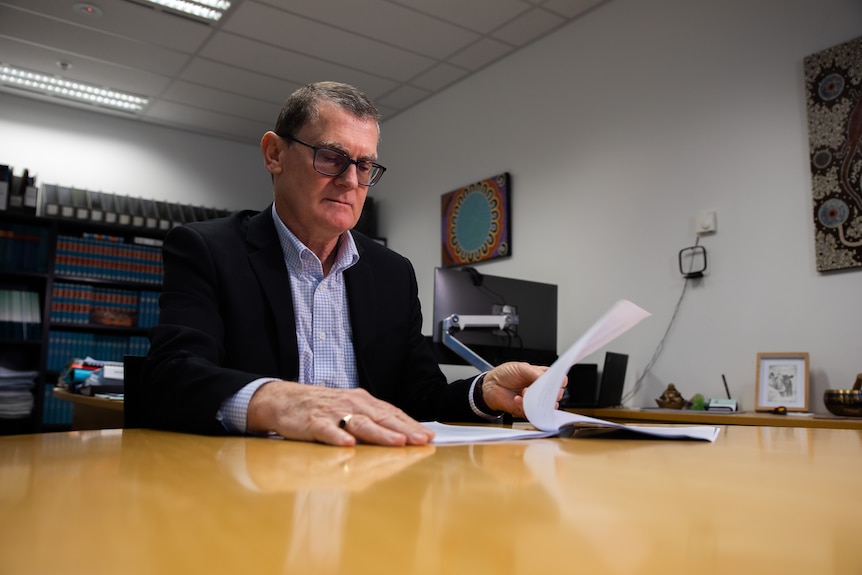 Eamon Ryan sitting at a table reading a report.