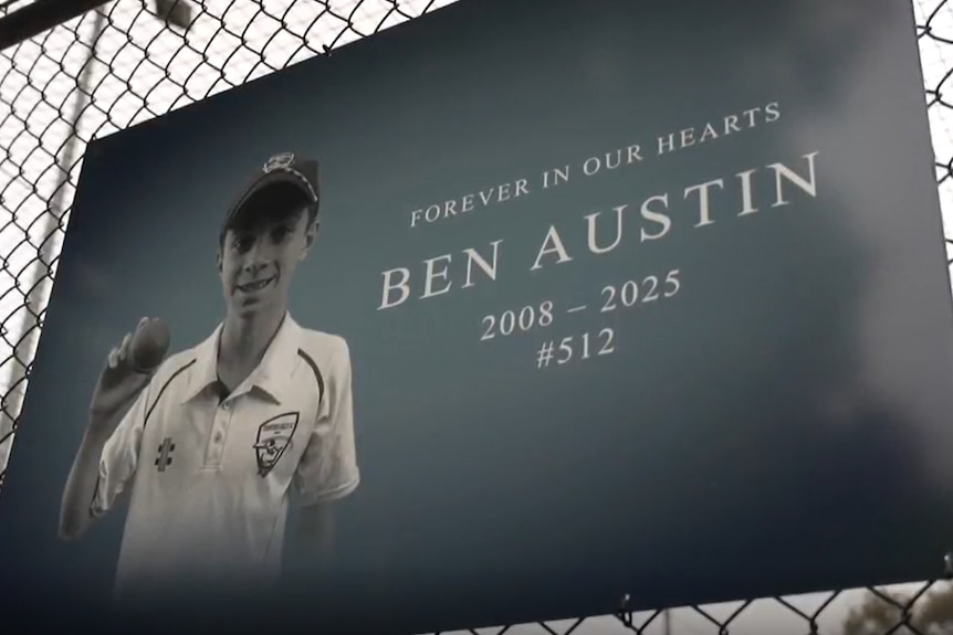 A sign on a fence features the name and image of Ben Austin.
