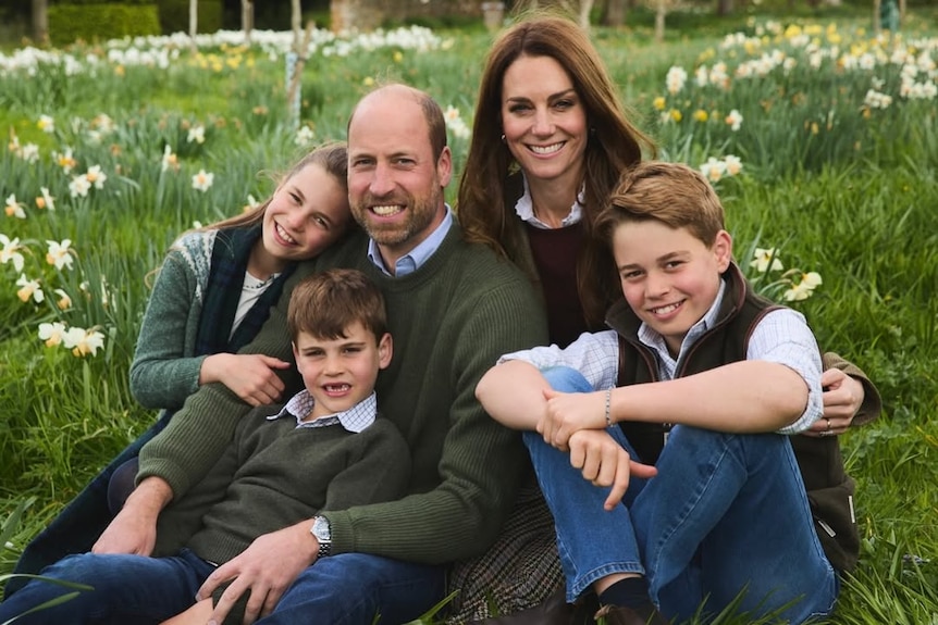 Prince William, Princess Catherine and their children, George, Charlotte and Louis, sit in a field and smile