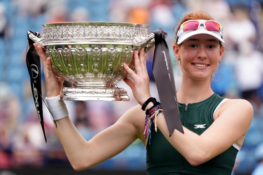 Maya Joint smiles while holding up a large trophy