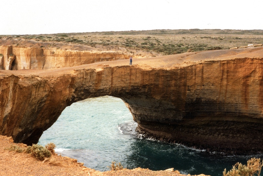 A limestone structure called London Bridge with natural bridge arch with man standing on it