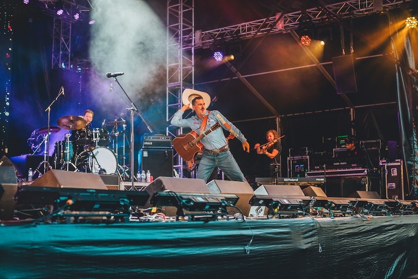 A musican performing with a band about through a hat into the crowd