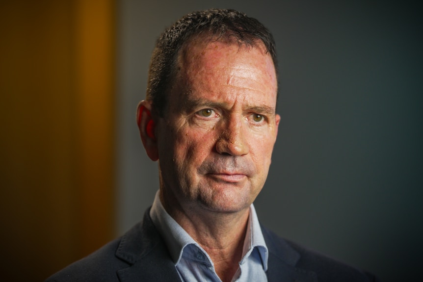 A middle-aged man looking sternly off to the side.