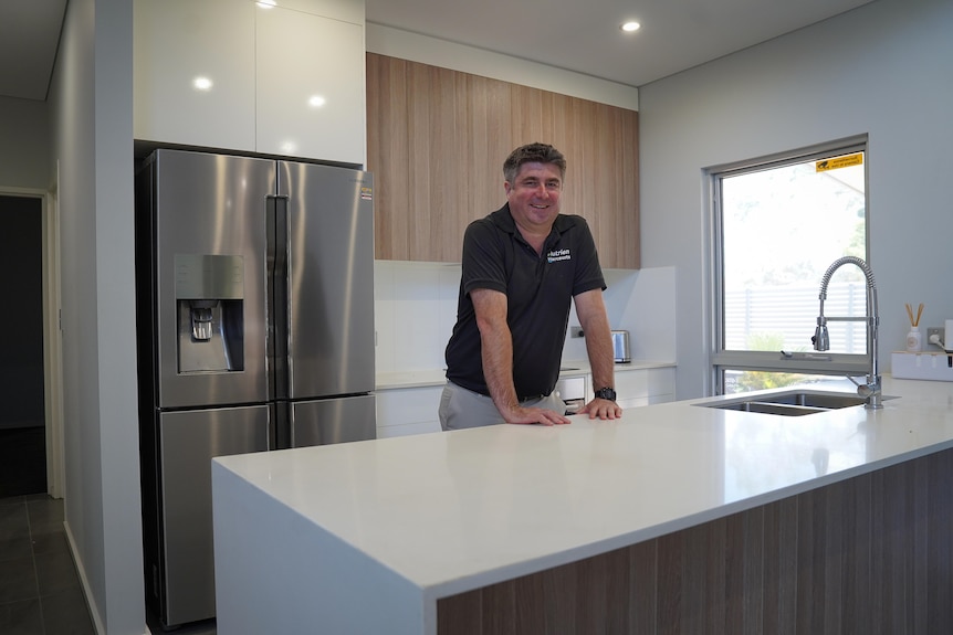 A man stands behind a kitchen counter