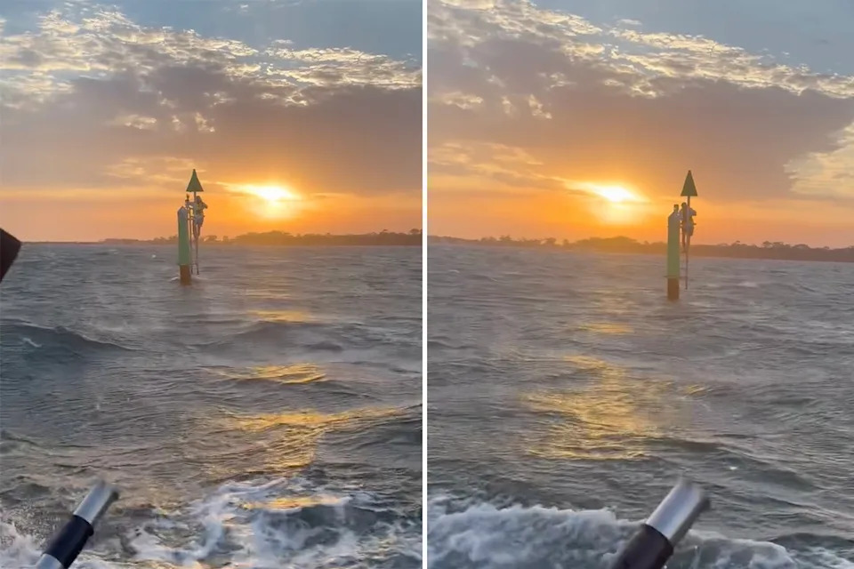A man clings to a pole several kilometres off the coast of Victoria. The sun is starting to set behind him.