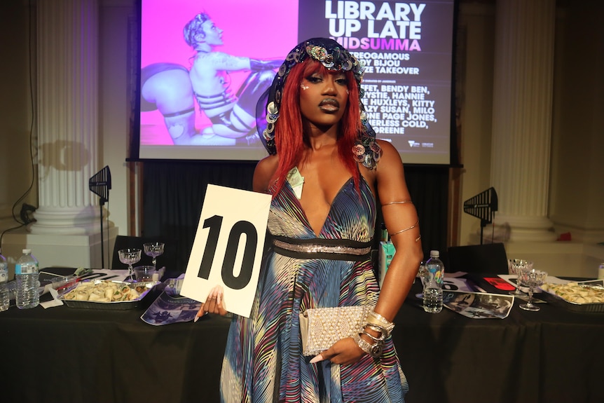 A person looking glamorous while holding up a sign saying 10.