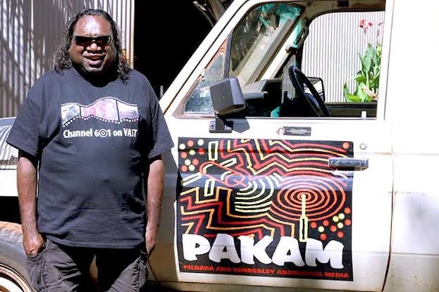 Indigenous man standing in front a car