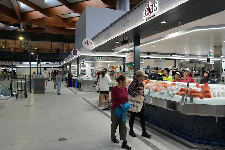people walk in market looking at empty food cabinets