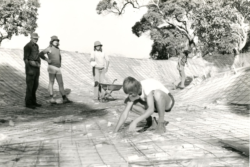 A black and white photograph of people securing mesh for concrete pouring. 