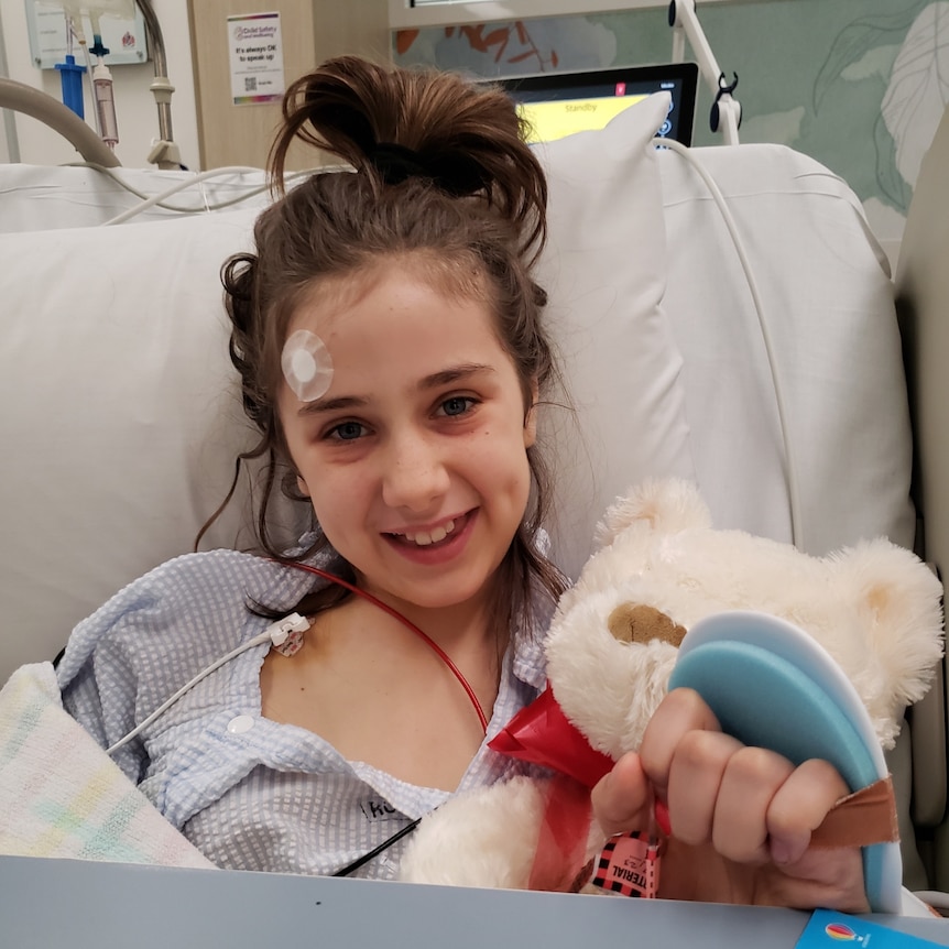 A young girl smiling as she receives treatment in hospital.