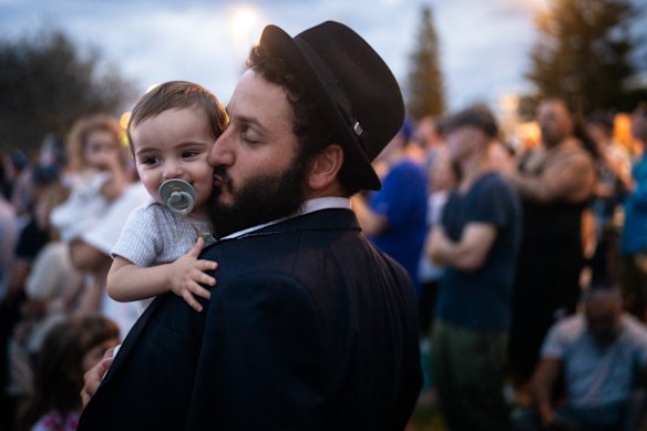 Rabbi Yacov Harkham and his son, Ariel, embrace among thousands during a candlelight vigil at Bondi Beach on December 21.