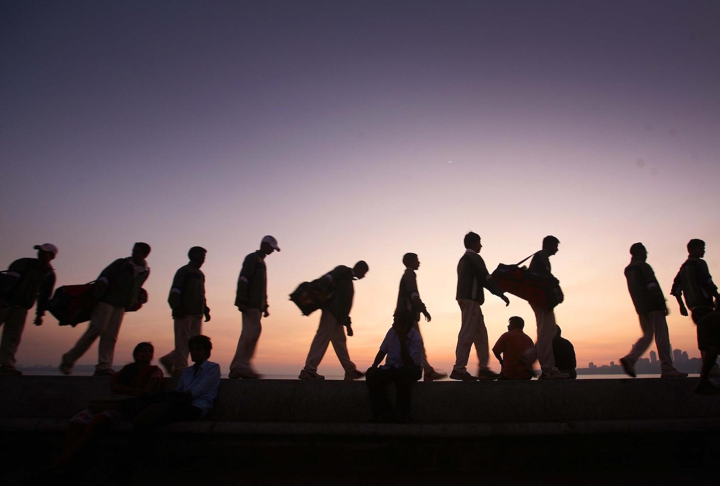 Don't let the sun go down on me: children lug their bags home along Mumbai's Marine Drive after a long day of cricket