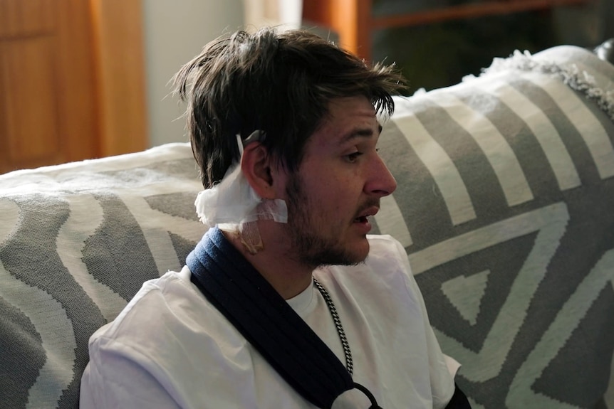 Kaleb Macqueen sits and talks to media after he survived a shooting the side of his head shows a bandage