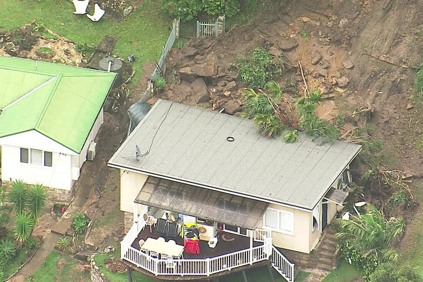 A landslide streams down onto a property on a hill