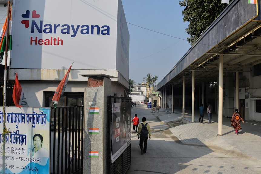 People walk down a concrete driveway of a large facility
