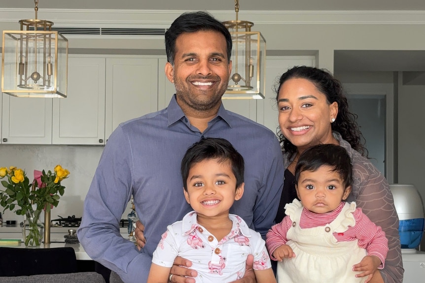 Family of four stands smiling in kitchen