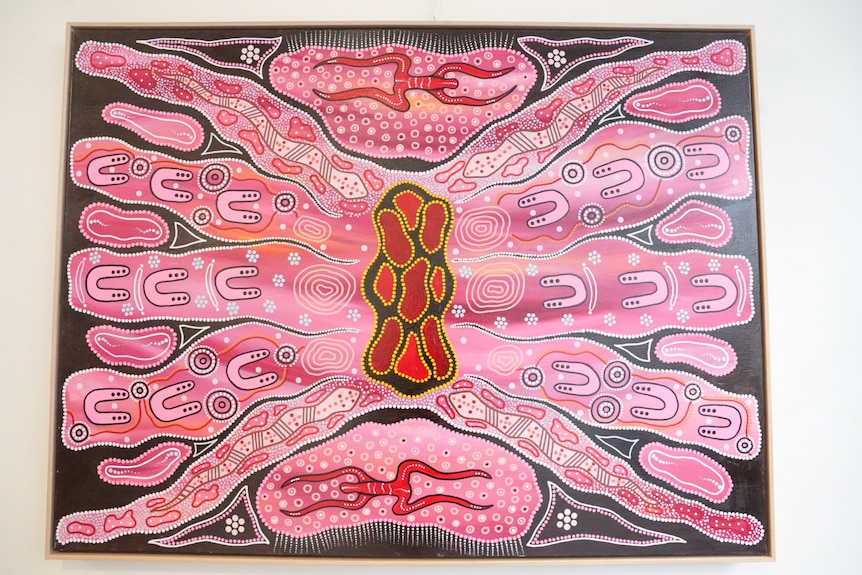 Pink Aboriginal artwork depicting people around a fire which is in the middle of the painting.