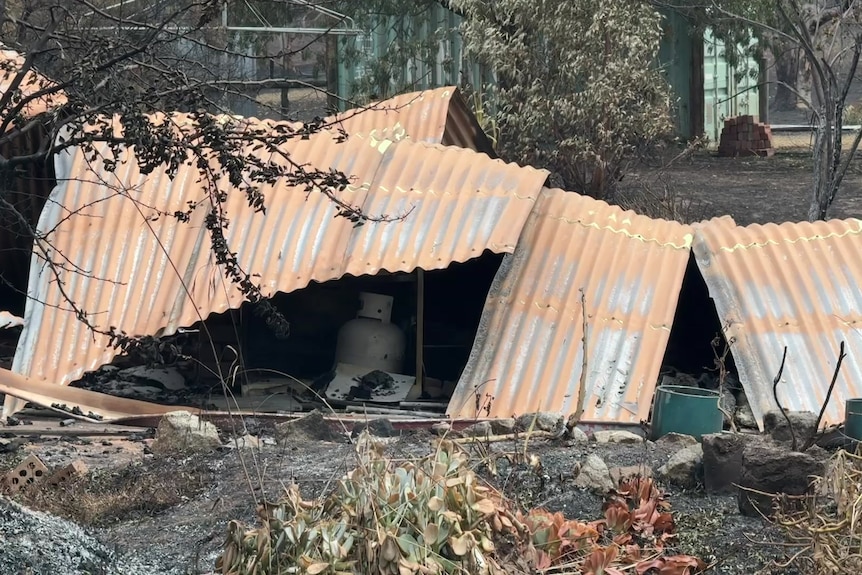 Pieces of tin roof on charred ground.