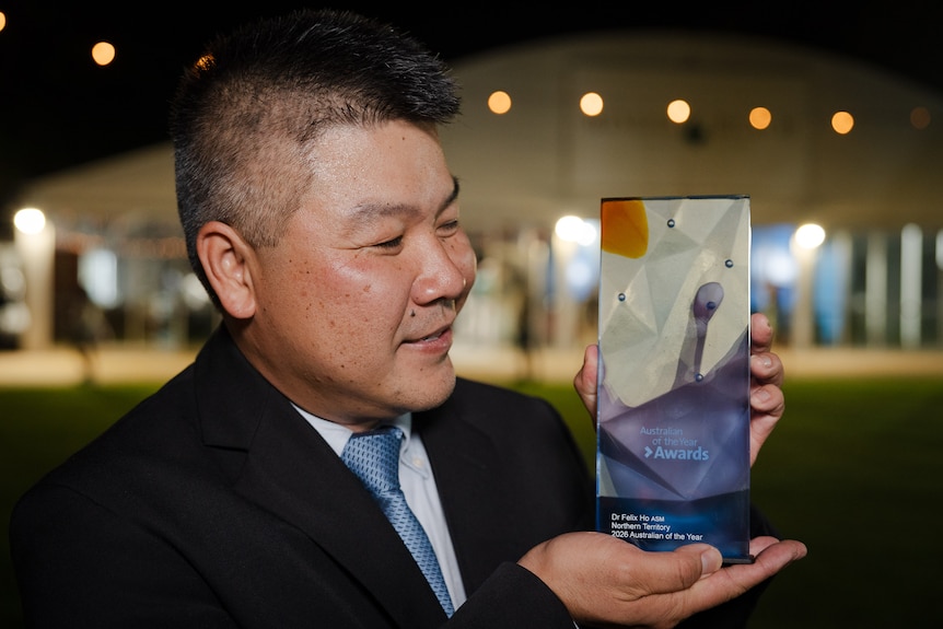 A man looks at his award. 