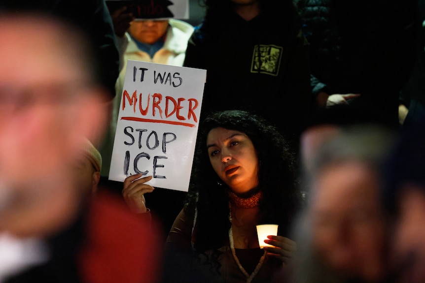 A woman holding a protest sign saying "It was murder. Stop ICE".