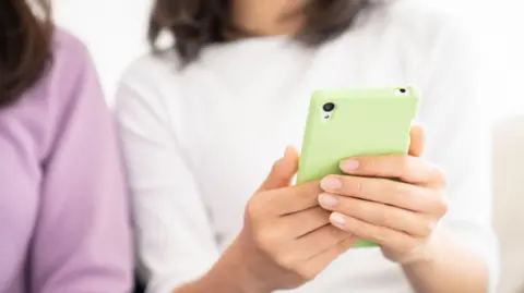Getty Images Two hands are seen holding a mint green smartphone.