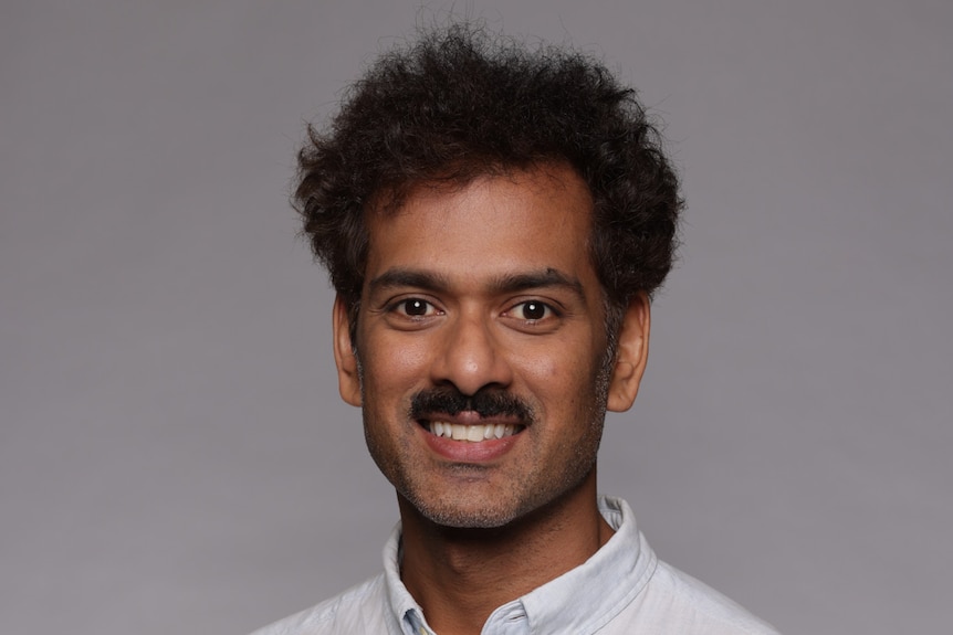 Deshan Sebaratnam poses in a white linen shirt.