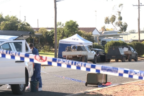 A crime scene with police tape, and vehicles.